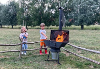Twee kinderen roosteren marshmallows boven een vuur bij Feather Down Landgoed ter Wijnendale, West-Vlaanderen.