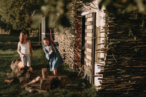 Two children splitting wood beside a rustic shed at Feather Down Landgoed ter Wijnendale holiday park.