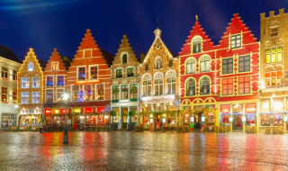 Fachadas históricas y coloridas iluminadas de noche en una plaza cerca de Zedelgem, Flandes Occidental, Bélgica.