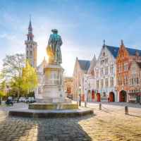 Plaza histórica con estatua y edificios coloridos bajo la luz del sol en una pintoresca ciudad europea.