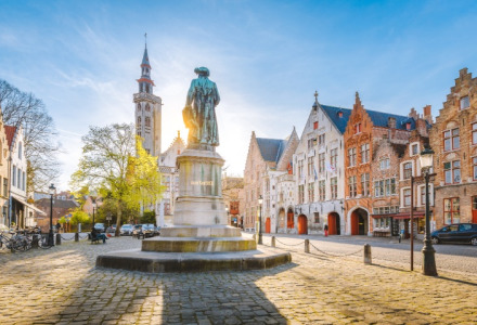 Place historique avec une statue et des bâtiments colorés sous le soleil dans une ville européenne charmante.