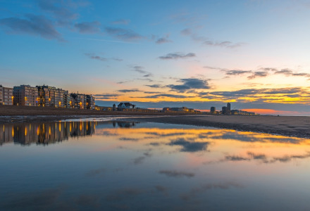 Atardecer en un parque vacacional junto a la playa con alojamientos glamping y reflejos en el agua.
