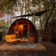 Acogedora tiny house Boshuys con sofá naranja frente a la casa, situada en el bosque de Buitengoed Ruysbos.
