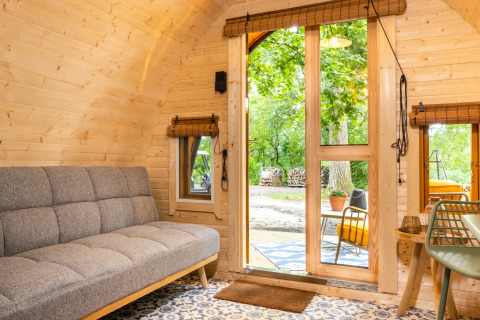 Interior de la tiny house Boshuys en Buitengoed Ruysbos, con paredes de madera y vista al exterior verde.