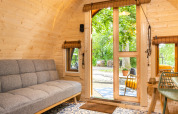 Interior de la tiny house Boshuys en Buitengoed Ruysbos, con paredes de madera y vista al exterior verde.