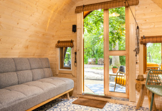 Interior of the Boshuys tiny house at Buitengoed Ruysbos, with wooden walls and a view of the outdoors.