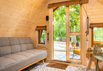 Interior de la tiny house Boshuys en Buitengoed Ruysbos, con paredes de madera y vista al exterior verde.