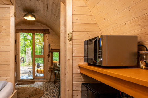 Interior of Boshuys tiny house at Buitengoed Ruysbos, Netherlands, with microwave and outdoor view.