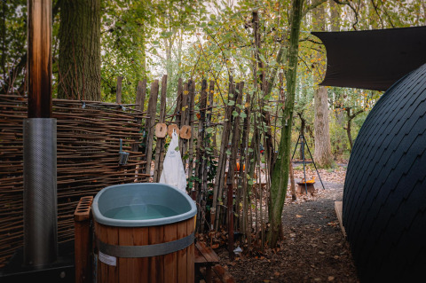 Außenbadewanne und Sauna neben einem kleinen Haus im Wald bei Boshuys, Buitengoed Ruysbos, Niederlande.