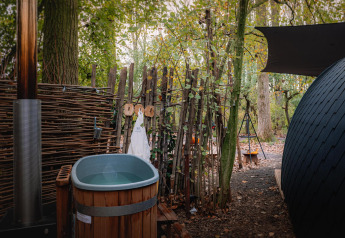 Vasca all'aperto e sauna accanto a una tiny house nei boschi di Boshuys, Buitengoed Ruysbos, Paesi Bassi.