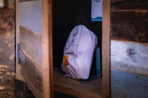 Eine Papiertüte steht auf einem Regal in einem kleinen Holzschrank im Boshuys, einem Tiny House in Ruysbos.
