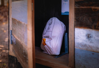 Eine Papiertüte steht auf einem Regal in einem kleinen Holzschrank im Boshuys, einem Tiny House in Ruysbos.