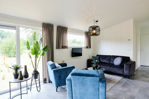 Moderne woonkamer in Sand Lodge bij Holiday Park De IJsvogel met blauwe stoelen, Nederland.