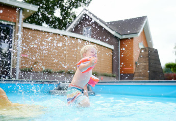 Kleines Kind spielt mit Schwimmflügeln im Pool am Sand Lodge im Holiday Park De IJsvogel in den Niederlanden.