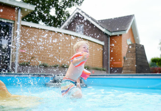 Niño pequeño chapoteando en la piscina con flotadores en Sand Lodge, Holiday Park De IJsvogel, Países Bajos.