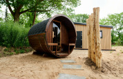 Sand Lodge Sauna au Holiday Park De IJsvogel, Pays-Bas, avec sauna tonneau et micro-maison en bois.