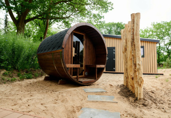 Sand Lodge Sauna at Holiday Park De IJsvogel in the Netherlands, featuring a barrel sauna and tiny house.