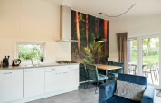 Cocina y comedor modernos en tiny house, decoración mural de bosque, muebles elegantes y vista al jardín.