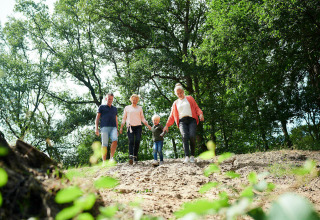 Een familie wandelt een heuvel af tussen de bomen, genietend van de natuur bij een tiny house.