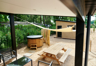 Terrasse mit Whirlpool, Picknicktisch und Sonnensegel bei Sand Lodge Jacuzzi im Holiday Park De IJsvogel, Niederlande.