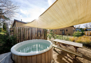 Buitenjaccuzi en picknicktafel bij Sand Lodge Jacuzzi, Holiday Park De IJsvogel, Nederland, met zonnedoek.