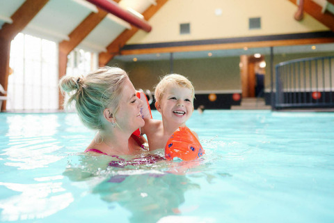 Mujer y niño se divierten en la piscina cubierta de Sand Lodge Jacuzzi, Holiday Park De IJsvogel, Países Bajos.