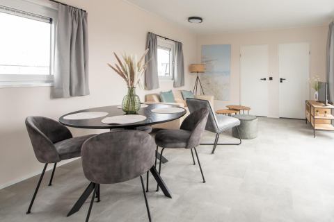 Soggiorno moderno alla Wood Lodge presso Kompas Camping Nieuwpoort, Belgio, con arredi eleganti e zona pranzo.