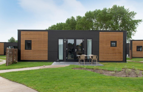 Moderne træhytte med udendørs siddeområde på Kompas Camping Nieuwpoort, Belgien, hunde tilladt.