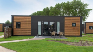 Moderne houten lodge met terras en zitje bij Kompas Camping Nieuwpoort in België, honden toegestaan.