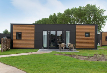Moderne træhytte med udendørs siddeområde på Kompas Camping Nieuwpoort, Belgien, hunde tilladt.