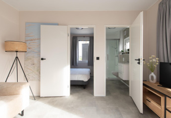Indvendigt billede af Wood Lodge med åbne døre til soveværelse og badeværelse på Kompas Camping Nieuwpoort.