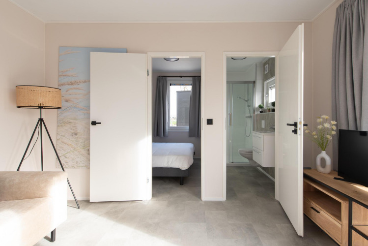 Binnenfoto van Wood Lodge met open deuren naar slaapkamer en badkamer op Kompas Camping Nieuwpoort.