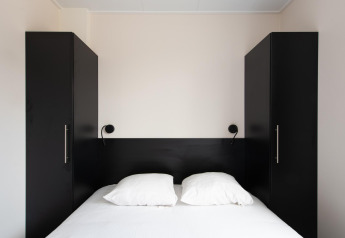 Modernes Schlafzimmer mit Doppelbett, schwarzen Schränken und Lampen im Wood Lodge, Kompas Camping Nieuwpoort.