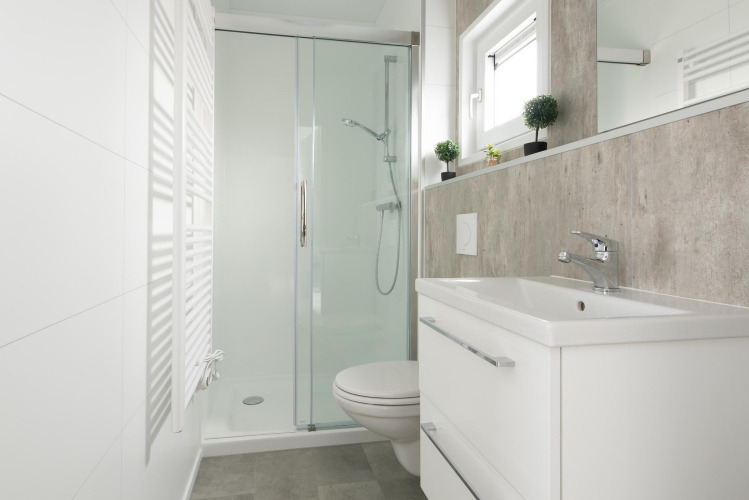 Bagno moderno e compatto con doccia, lavandino, WC e piccole piante al Kompas Camping Nieuwpoort in Belgio.