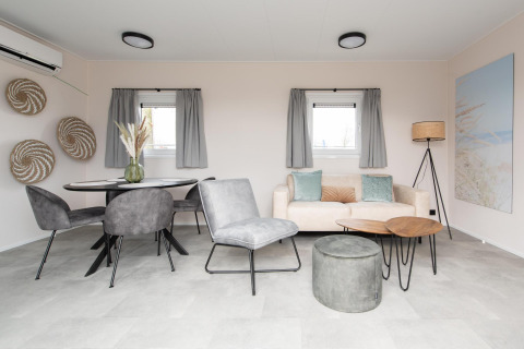 Moderne stue i Wood Lodge på Kompas Camping Nieuwpoort, Belgien, med stilfuld indretning og gråt interiør.