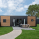 Moderne lodge med sort og træbeklædning, udendørs spisebord og grøn græsplæne foran indgangen.
