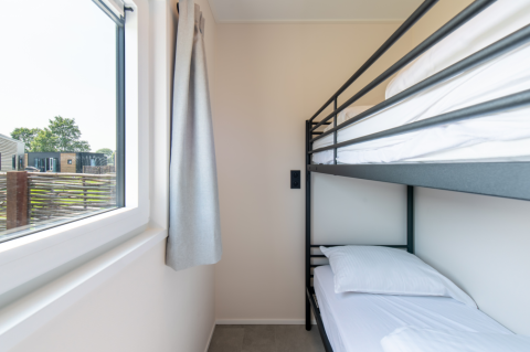 Indvendigt billede af et værelse med køjeseng og stort vindue på Wood Lodge, Kompas Camping Nieuwpoort.
