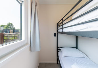 Innenaufnahme eines Zimmers mit Etagenbett und großem Fenster in der Wood Lodge, Kompas Camping Nieuwpoort.