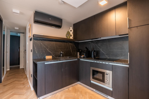 Modern kitchen with dark cabinets, built-in oven, and marble backsplash at Enzian Hottub, Ossiacher See.