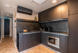 Cucina moderna con mobili scuri, forno incassato e paraschizzi in marmo presso Enzian Hottub a Ossiacher See.