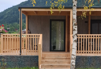 Entrée du lodge Enzian Hottub au lac Ossiacher en Autriche, avec terrasse en bois et vue sur la nature.
