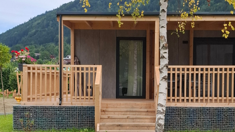 Ingresso della lodge Enzian Hottub all’Ossiacher See in Austria, con veranda in legno e vista natura.