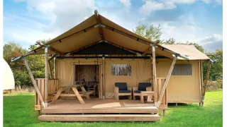 Luxury Safari Lodge at Buitencentrum Hessenheem, Netherlands, exterior view with wooden terrace and chairs.