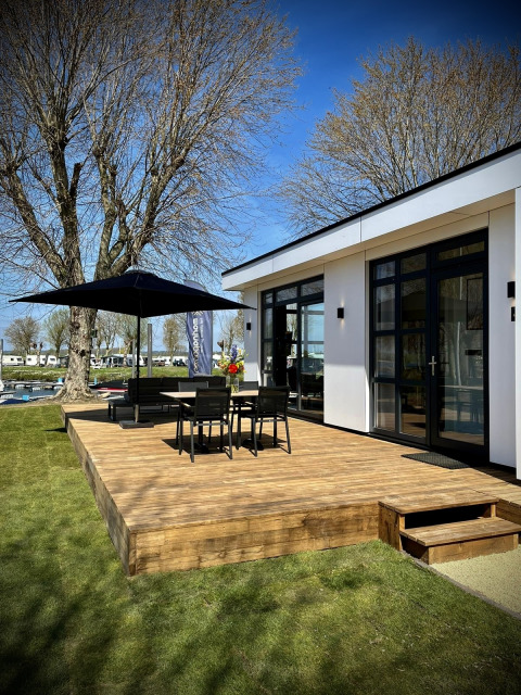 Terrazza soleggiata di Villa Maritiem al MarinaPark Bad Nederrijn, Paesi Bassi, con tavolo e ombrellone.