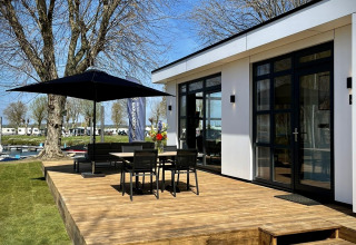 Terraza soleada de Villa Maritiem en MarinaPark Bad Nederrijn, Países Bajos, con muebles y sombrilla.