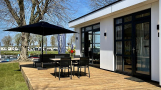 Terrazza soleggiata di Villa Maritiem al MarinaPark Bad Nederrijn, Paesi Bassi, con tavolo e ombrellone.