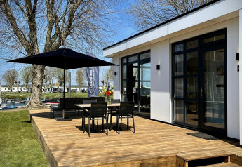 Terraza soleada de Villa Maritiem en MarinaPark Bad Nederrijn, Países Bajos, con muebles y sombrilla.