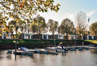 Cabañas junto al agua en Villa Maritiem, MarinaPark Bad Nederrijn, Países Bajos, con barcos en el muelle.