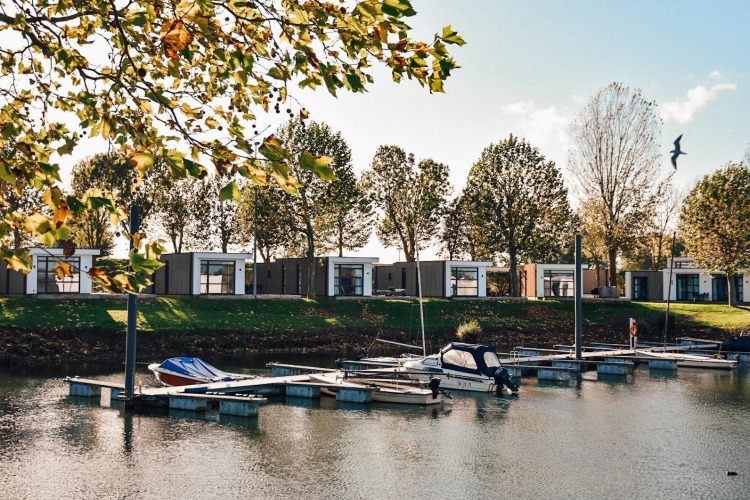 Moderne Villen am Wasser bei MarinaPark Bad Nederrijn, Niederlande, mit Booten am Anlegesteg.
