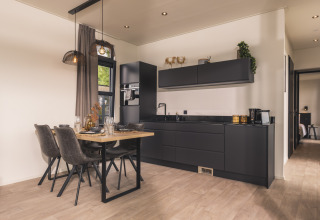 Cocina moderna y comedor en el lodge Villa Maritiem, con muebles negros y decoración elegante y contemporánea.